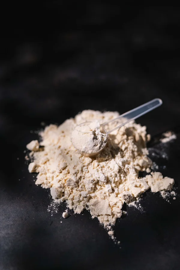 Produktfotografie Regensburg – helles Pulver mit Scoop auf dunklem Hintergrund